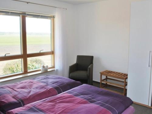 a bedroom with a bed and a chair and a window at Ferienwohnung Delfs in Hamdorf