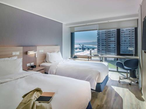 Una habitación de hotel con dos camas, un escritorio y una ventana. en Pullman Vina del Mar San Martin, en Viña del Mar