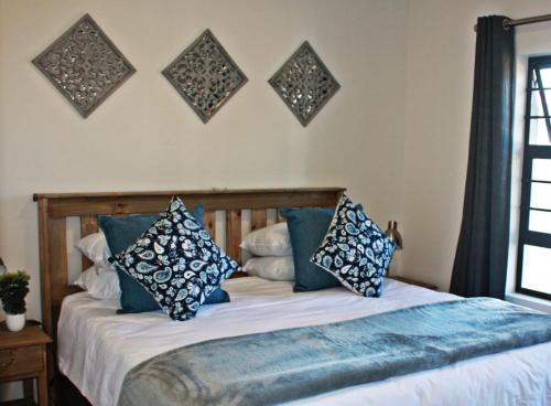 ein Bett mit blauen und weißen Kissen darauf in der Unterkunft Gable Cottages 3 in Clarens
