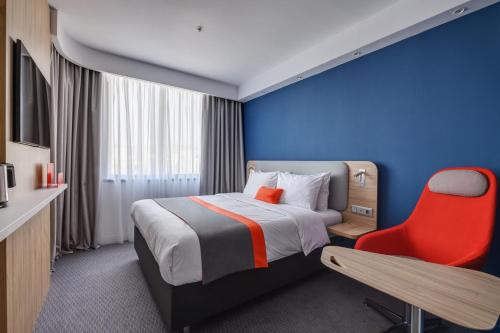 a hotel room with a bed and a red chair at Holiday Inn Express - Almaty, an IHG Hotel in Almaty