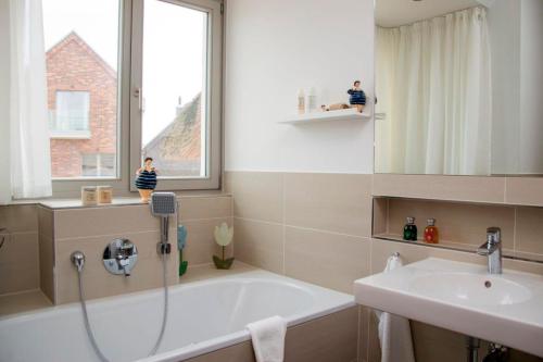 ein Bad mit einer Badewanne, einem Waschbecken und einem Fenster in der Unterkunft Ostsee - Reetdachhaus Nr 10 "Reethus Sonnendüne" im Strand Resort in Heiligenhafen