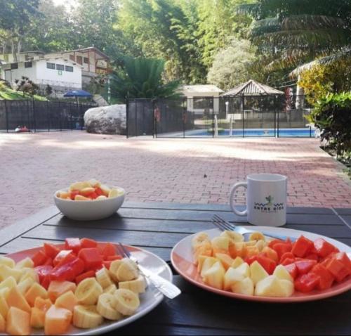 a table with two plates of fruit and a cup of coffee at Eco Hotel Entre Ríos in Villeta