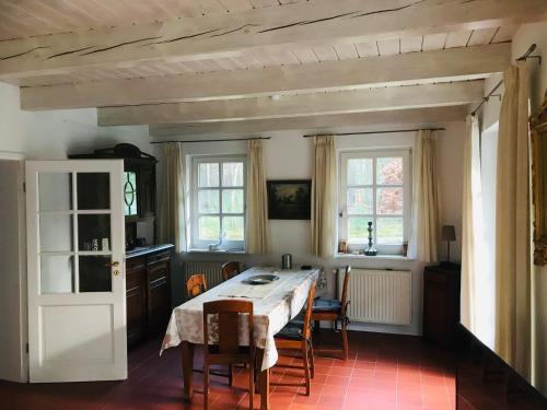 ein Esszimmer mit einem Tisch, Stühlen und Fenstern in der Unterkunft Vesta Waldhaus Bardowicker Heide in Bardowick