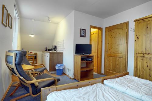 ツィングストにあるWaldesruh - App2のベッドルーム(ベッド1台、椅子、テレビ付)