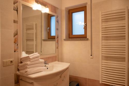 y baño con lavabo, espejo y toallas. en Fewo Dreiraum im Haus Götsch 2, en Parcines