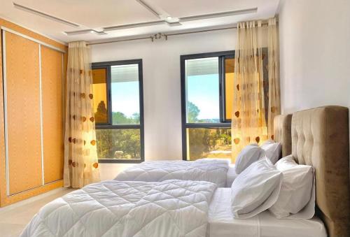 1 dormitorio con 2 camas y ventanas grandes en Appart AYAMOUS MARINA en Kenitra