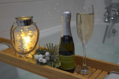 a bottle of wine and a glass on a shelf at Corner Cottage - character, charm, great location. in Ringwood
