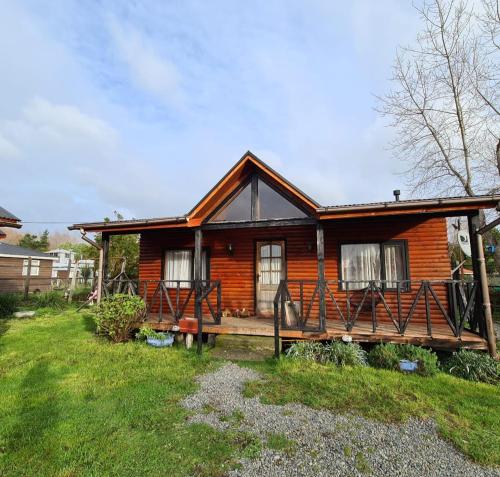 a wooden house with a porch on a yard at Cabañas Kompatzki in Ancud