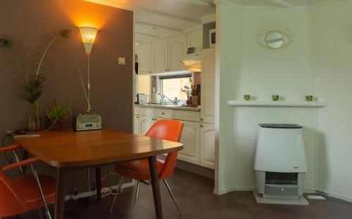 una cocina con mesa de madera, sillas naranjas y barra. en FoREST, en Zuidlaren