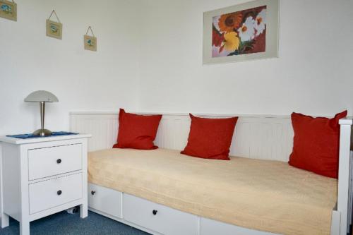 ヴァンガーオーゲにあるOsterdüne 63のベッドルーム1室(赤い枕とナイトスタンド付きのベッド2台付)