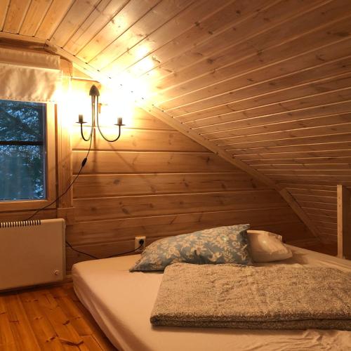 a bed in a room with a wooden wall at Himalayan cabin Inkoo in Inkoo