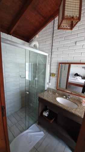 a bathroom with a shower and a sink and a mirror at Villa dos Ganchos in Governador Celso Ramos