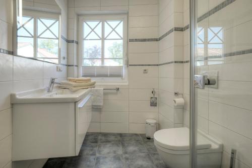 a white bathroom with a toilet and a sink at Villa Obendtied, FW 3 in Zingst