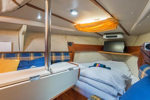 Habitación pequeña con cama y TV. en Pequeño velero en Port Forum ideal para Backpackers en Barcelona