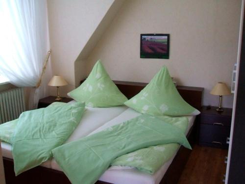 Schlafzimmer mit einem Bett mit grüner Bettwäsche und Kissen in der Unterkunft Frauke Bruhn in Fockbek