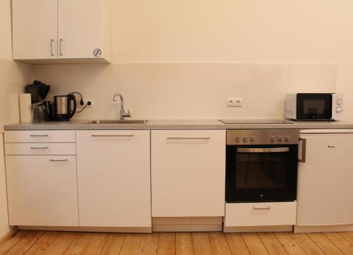 La cuisine est équipée de placards blancs et d'un four. dans l'établissement Haus Roy Ferienwohnung 1Etage, à Zülpich