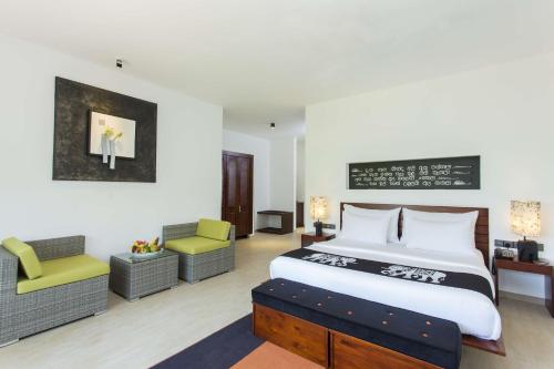 a hotel room with a large bed and a large chair at Aliya Resort and Spa in Sigiriya