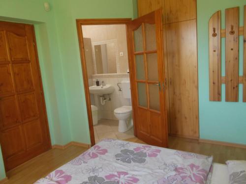 a bedroom with a bed and a bathroom with a toilet at Hétkanyar Vendégház in Nagyvázsony
