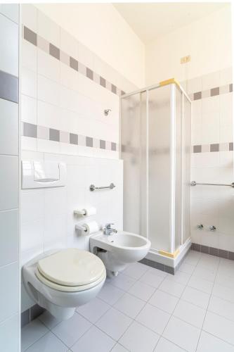a white bathroom with a toilet and a sink at Il Seminario in Alba