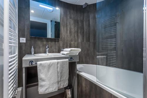 a bathroom with a sink and a tub and a mirror at Hôtel des Marais Salants in Batz-sur-Mer