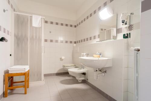 a white bathroom with a sink and a toilet at Il Seminario in Alba