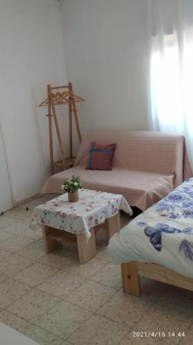 a room with two beds and a table and a couch at Jordan Valley one room apartment in Menaẖemya