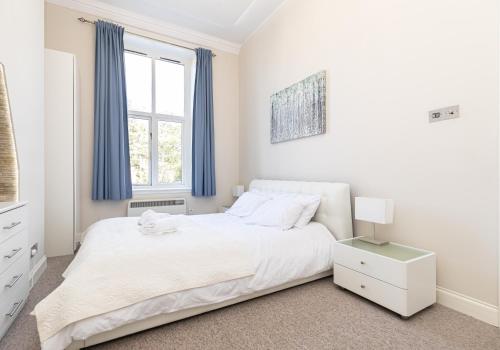 a white bedroom with a bed and a window at Holiday Beach Flat in Bournemouth, England, UK in Bournemouth
