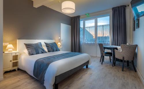 a hotel room with a bed and a desk and a window at Hôtel des Marais Salants in Batz-sur-Mer