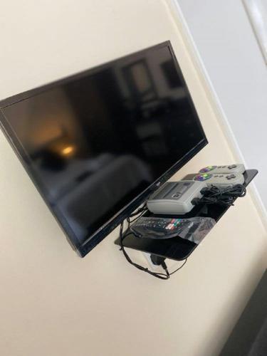 a flat screen tv with a remote control on a shelf at Burlington Hotel in Sandown