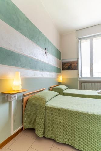 two beds in a room with green and white walls at Il Seminario in Alba