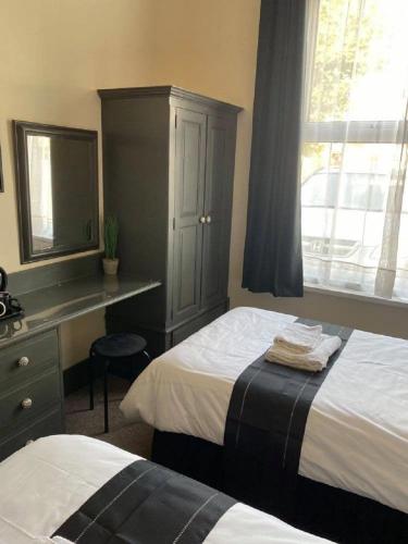 a bedroom with a bed and a desk and a window at Burlington Hotel in Sandown