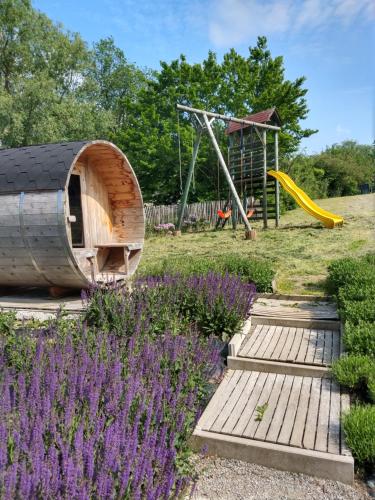 a garden with a playground with purple flowers at Maison Durbuy L'air du temps in Weris