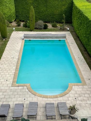 a large swimming pool with four chairs next to it at La Métairie in Vernou-sur-Brenne