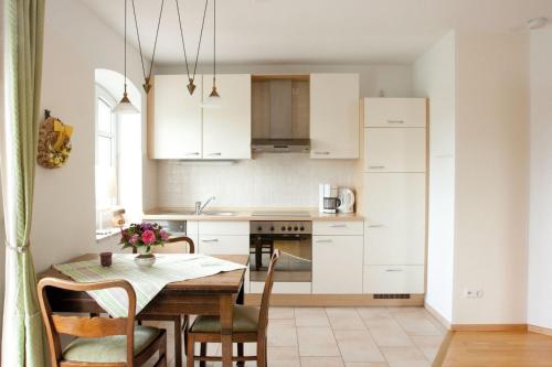 una cocina con armarios blancos y una mesa con sillas. en Fewo 2 "Landhaus am Grashof" en Offenbüttel