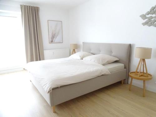 - une chambre avec un lit doté de draps blancs et une fenêtre dans l'établissement Küstenperle, à Grömitz