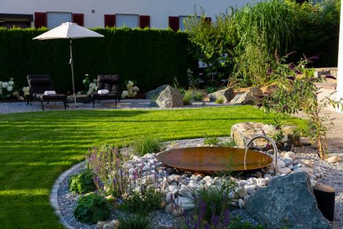 a garden with an umbrella and a table and chairs at Hotel Bergidyll in Pfronten