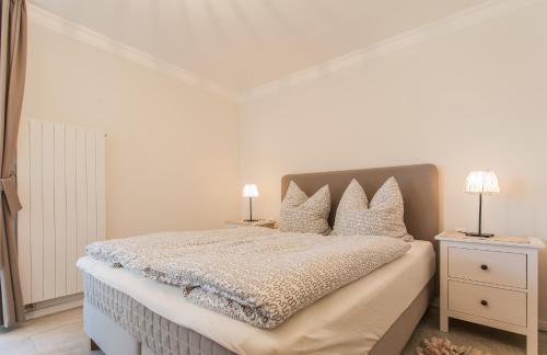 a white bedroom with a bed with two night stands at Whg 05 - Boddenangler in Zingst