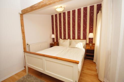 a bedroom with a white bed with a striped wall at Strandnelke in Dahme