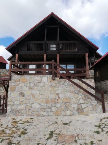 a log cabin with a stone wall in front of a building at Chalé 41 in Cortes do Meio