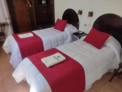 Habitación de hotel con 2 camas con sábanas rojas y blancas en Hotel Romi en Colonia del Sacramento