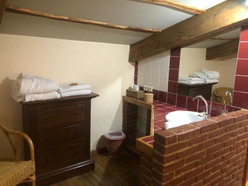 a bathroom with a sink and a brick wall at Restaurant et Chambres d'Hôtes La Ferme de Cornadel in Anduze