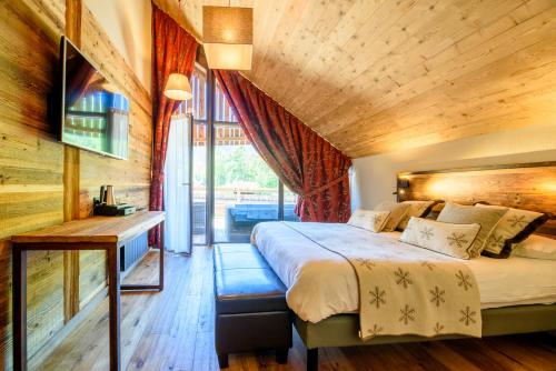 Un dormitorio con una cama grande con techo de madera. en Hôtel Neste de Jade, en Saint-Lary-Soulan