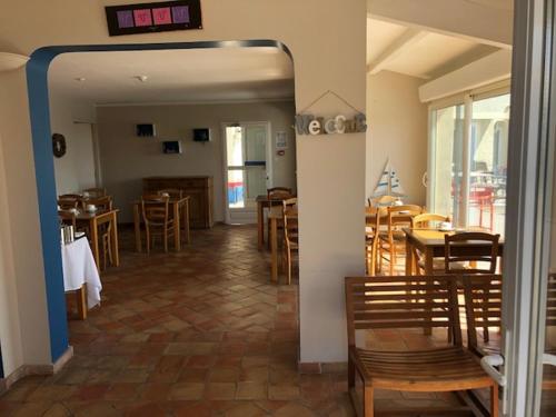 un restaurante con mesas y sillas y un reloj en la pared en Hotel Le Bleu Marine en Saintes-Maries-de-la-Mer