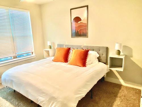 ein weißes Bett mit orangefarbenen Kissen im Schlafzimmer in der Unterkunft Pristine Apt-King Bed-Access to 3 Las Vegas Pools! in Bryan