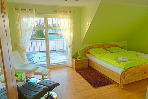 ein grünes Schlafzimmer mit einem Bett, einem Stuhl und einem Fenster in der Unterkunft Haus Kathrin in Zingst