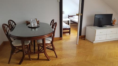 a dining room table with chairs and a television at Green Wood Apartament Stara Ochota in Warsaw