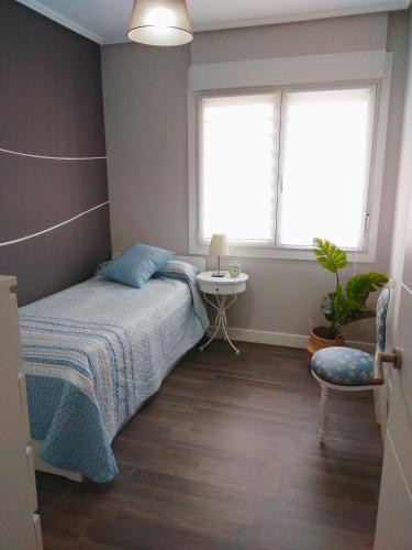 a bedroom with a bed and a table and a window at Aixula Lekeitio - Garaje opcional, reformado y céntrico in Lekeitio