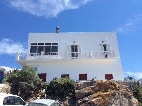 a white house on a hill with cars parked in front at Olympia in Mikonos