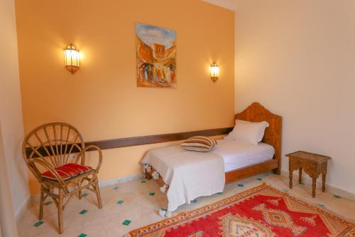 a bedroom with a bed and a chair and a table at Upupa de l’Atlas in Marrakech