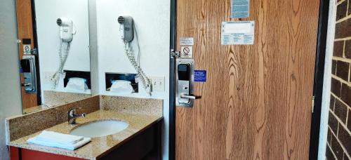 a bathroom with a sink and a phone next to a door at Reliance Inn in Wausau